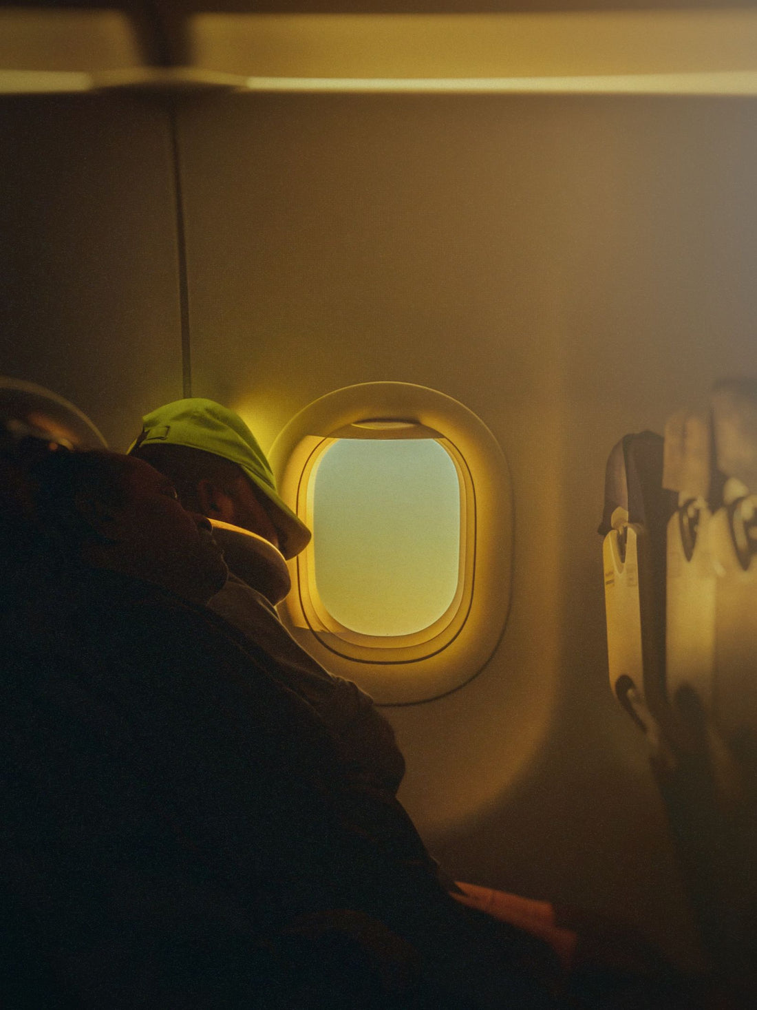 Person resting beside an airplane window during travel