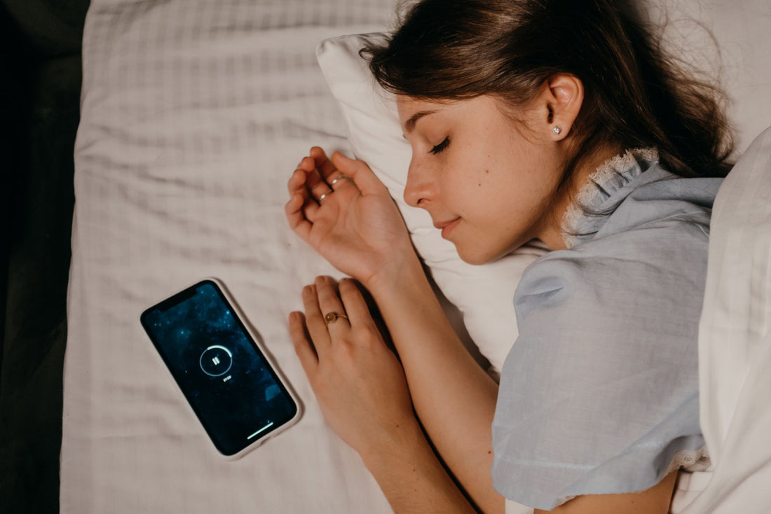 Woman sleeping beside a phone during a bedtime routine
