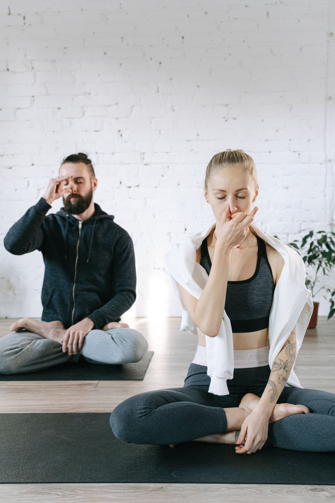 Two people practicing breathing exercises indoors